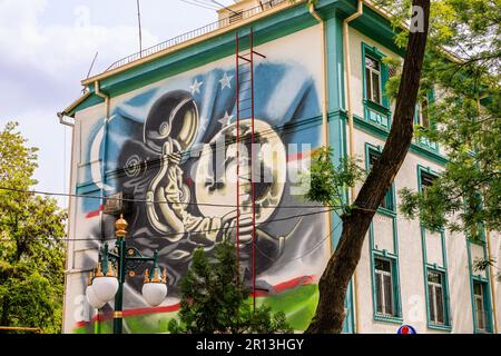 street art mural du cosmonaute russe yuri gagarin dans l'espace en costume en orbite au-dessus de la terre dans vostok 1 capsule dans la rue gagarin tachkent sa statue à proximité Banque D'Images
