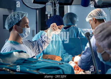 Une équipe de chirurgiens effectuant soigneusement la chirurgie en utilisant des instruments précis dans la salle d'opération sauver la vie du patient, un travail d'équipe clair. Banque D'Images