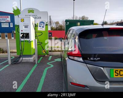 Un véhicule électrique Nissan Leaf se charge à un chargeur rapide Pod point dans un parking de supermarché Lidl à Barnstaple, North Devon, Angleterre. Banque D'Images