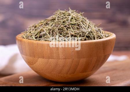 Feuilles de romarin aux herbes séchées. Assaisonner le romarin sur fond de bois. Épices et herbes pour la cuisine, herbes de provence. Gros plan Banque D'Images