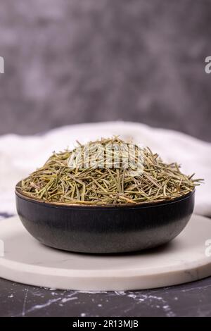 Feuilles de romarin aux herbes séchées. Assaisonner le romarin sur fond sombre. Épices et herbes pour la cuisine, herbes de provence. Gros plan Banque D'Images