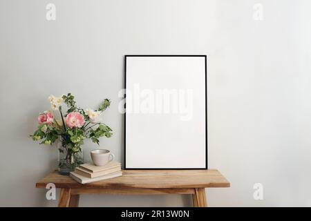 Maquette de cadre noir vierge. Table artistique, banc de bois encore la composition de vie avec tasse de café, vieux livres. Bouquett de printemps de tulipes roses Banque D'Images