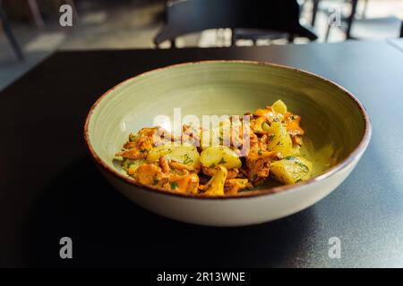 Chanterelles frites avec pommes de terre bouillies et herbes vertes, persil et aneth dans un bol pour le déjeuner. Banque D'Images