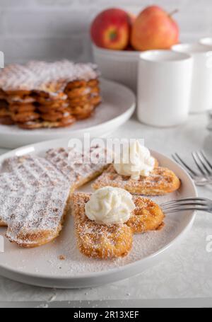 Gaufres fraîches avec sucre en poudre et crème fouettée sur la table de cuisine Banque D'Images