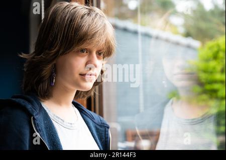 Portrait d'une jeune fille de 15 ans qui rêve à travers la fenêtre, Herentals, Belgique Banque D'Images