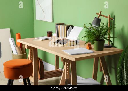 Lieu de travail de l'écrivain avec machine à écrire sur un bureau en bois près du mur vert pâle dans la chambre Banque D'Images