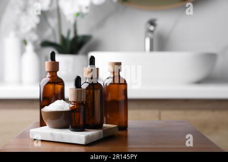 Huiles essentielles et sel de mer sur table en bois dans la salle de bains. Espace pour le texte Banque D'Images