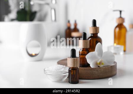Huiles essentielles, fleur d'orchidée et sel de mer sur comptoir blanc dans la salle de bains. Espace pour le texte Banque D'Images