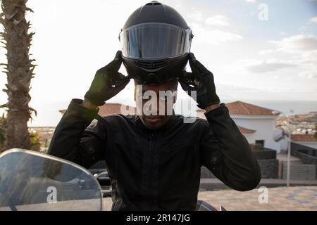 Gros plan sur un motard afro-américain prêt à monter avec son casque. Concept de sécurité routière Banque D'Images