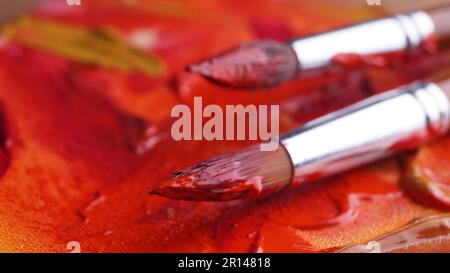 Pinceaux sur la palette de l'artiste avec des peintures mixtes, gros plan Banque D'Images