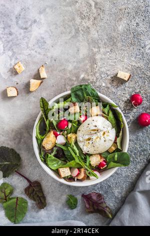 Salade mixte avec radis, croûtons faits maison et fromage burrata sur fond gris, vue de dessus avec espace copie Banque D'Images