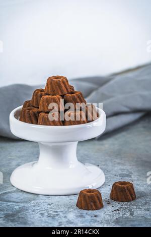 Pralines au chocolat sous forme de petits gâteaux Bundt, saupoudrés de cacao, sur fond gris clair, espace de copie Banque D'Images