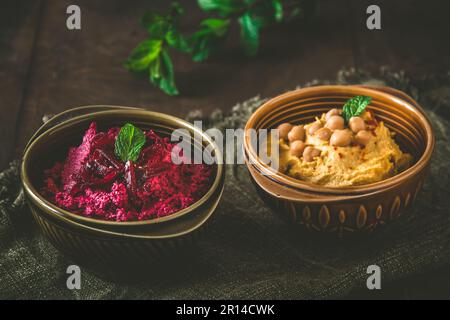 Bols avec houmous de betterave et houmous de pois chiches sur fond rustique en bois foncé Banque D'Images
