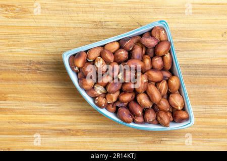 Cacahuètes grillées dans une assiette sur un plan de cuisine en bois. Banque D'Images
