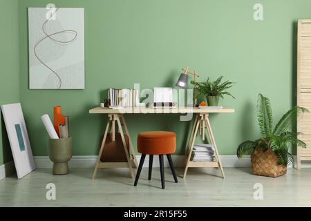 Lieu de travail de l'écrivain avec machine à écrire sur un bureau en bois près du mur vert pâle dans la chambre Banque D'Images