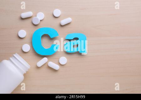 Papier symbole CA (calcium), bouteille médicale et pilules sur fond violet, vue de dessus Banque D'Images