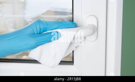 Homme en latex gants de nettoyage de la poignée de fenêtre avec un chiffon humide à l'intérieur, gros plan. Mesures de protection Banque D'Images