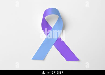 Journée mondiale de l'arthrite. Ruban de sensibilisation bleu et violet sur fond blanc, vue de dessus Banque D'Images