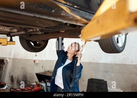 Je peux vous aider à garder votre voiture en marche pendant des années à venir. une femme mécanicien travaillant sous une voiture soulevée. Banque D'Images