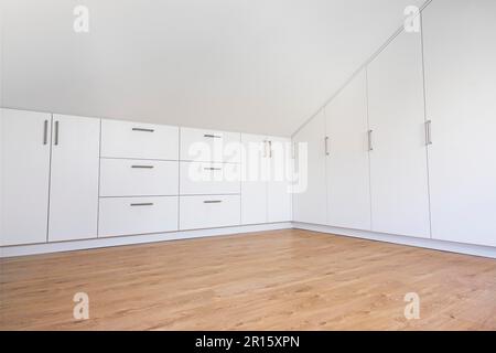 armoire moderne blanche intégrée dans une chambre vide avec plafond en pente Banque D'Images
