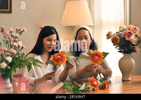 Jeune femme asiatique attrayante se joignant à l'atelier d'arrangement de fleurs fraîches avec sa mère. Concepts de loisirs et de temps familial Banque D'Images