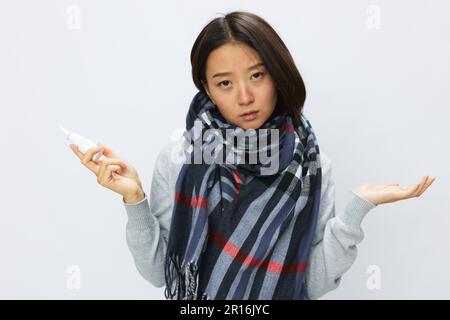 Femme asiatique grippe rhume avec nez bouché contient allergie et virus covid 19 spray nasal avec mal de gorge sur fond blanc Banque D'Images