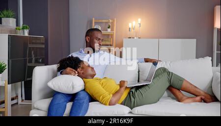 Jeune couple utilisant un ordinateur portable sur la table à la maison Banque D'Images