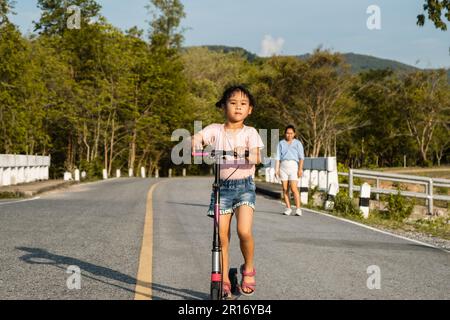 Jolie petite fille à cheval sur la route dans le parc extérieur. Sports sains et activités de plein air pour les écoliers en été. Banque D'Images