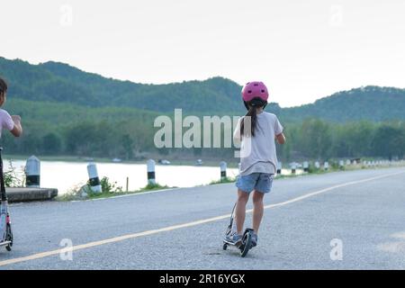 Jolie petite fille à cheval sur la route dans le parc extérieur. Sports sains et activités de plein air pour les écoliers en été. Banque D'Images