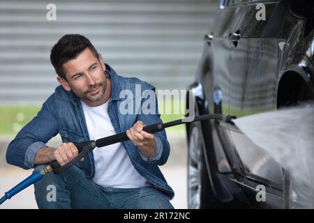 homme nettoyant automobile avec de l'eau haute pression Banque D'Images