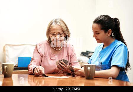 Vous jouez contre quelqu'un de sage... une femme âgée jouant des cartes avec son soignant. Banque D'Images