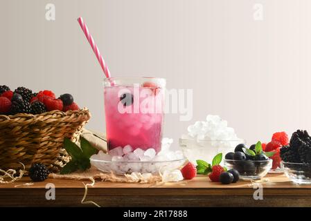 Buvez avec des baies avec des fruits et de la glace autour d'elle sur un banc de cuisine en bois et un arrière-plan isolé. Vue avant. Composition horizontale. Banque D'Images