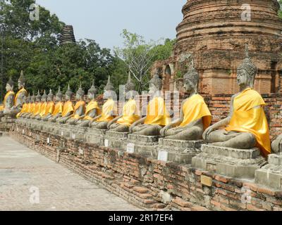 Thaïlande, Ayuthaya (anciennement la capitale royale 1350-1767): Rangée de figures de Bouddha décalées dans des robes de safran à Wat Yai Chai Mongkhon. Banque D'Images