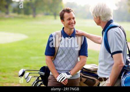 Père et fils discutant sur le terrain de golf. Père et fils ayant une discussion amicale sur le terrain de golf. Banque D'Images
