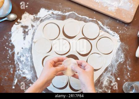 Mains de femme préparant des raviolis sur une table en bois Banque D'Images