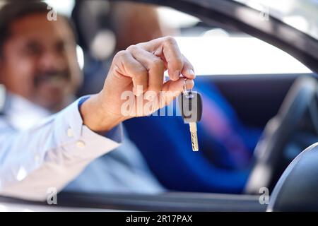 Prenons un disque. un homme âgé assis dans une voiture avec sa femme et vous montrant ses clés. Banque D'Images