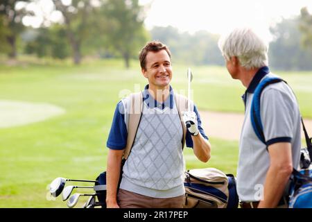 Père et fils sur le terrain de golf. Père et fils ayant une conversation amicale sur le terrain de golf. Banque D'Images