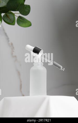 Flacon de sérum blanc avec pipette sur podium. Cosmétiques naturels pour le soin de la peau Banque D'Images