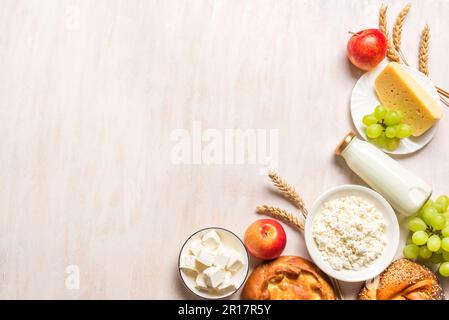 Happy Shavuot - concept religieux de vacances juives avec produits laitiers, fromage, pain traditionnel, bouteilles de lait, blé et fruits sur fond de bois blanc Banque D'Images