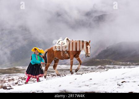 Femme avec un cheval aidant les touristes à atteindre Rainbow Mountain Banque D'Images