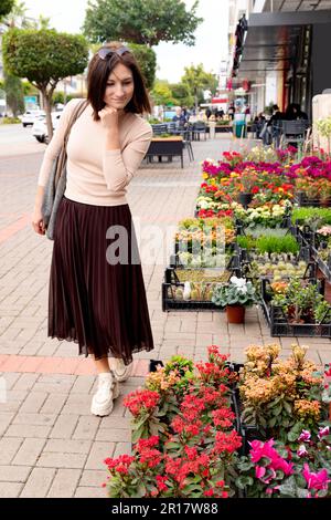 Jeune femme marchant dans le magasin de fleurs de la rue. Banque D'Images