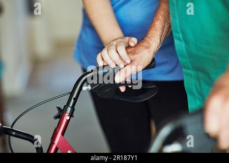 Theres grâce dans l'attention. une infirmière féminine méconnaissable qui assiste son patient senior qui utilise un marcheur pour le soutien. Banque D'Images