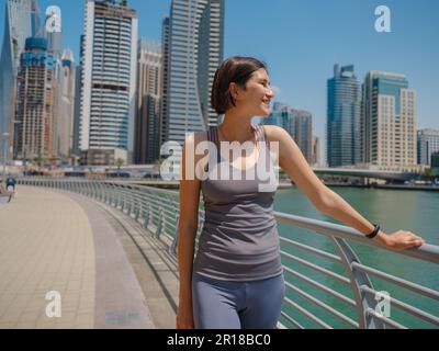 Ville en cours d'exécution - femme asiatique coureur, Dubai marina scène urbaine en arrière-plan. Athlète féminine, entraînement de jogging d'athlète de forme physique, vivre un mode de vie sain Banque D'Images