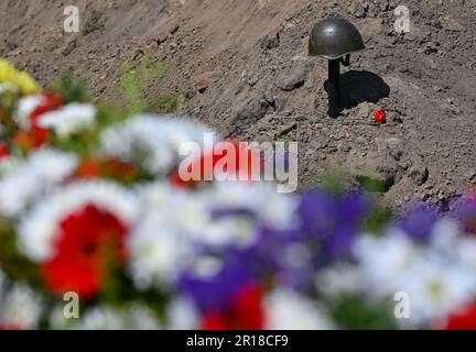 Lebus, Allemagne. 12th mai 2023. Un casque d'acier d'un soldat de l'Armée rouge de la Seconde Guerre mondiale et une carnation rouge peuvent être vus sur la tombe de la guerre soviétique. 78 ans après la fin de la Seconde Guerre mondiale, la Commission des sépultures de guerre avait mis 61 soldats de l'Armée rouge à Lebus (district de Märkisch-Oderland). Ils sont morts dans les batailles de l'Oderbruch et dans la bataille pour Berlin et ont été récupérés par la Commission des sépultures de guerre au cours des derniers mois. Credit: Patrick Pleul/dpa/Alay Live News Banque D'Images