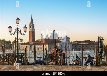 Photo prise d'un couple d'amoureux embrassant sur le front de mer du bassin de Saint-Marc avec l'île de San Giorgio Maggiore en arrière-plan, Venise Italie Banque D'Images