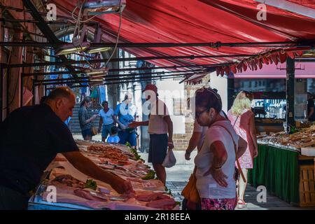 Lady achetant du poisson frais d'un fighmonger au marché du Rialto à Campo della Pescaria en été, Venise, Vénétie, Italie Banque D'Images