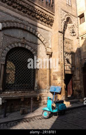 Un scooter Vespa vu garés à l'extérieur de Sabil-Kuttab de Katkhuda, dans la rue Al Muizz près du bazar Khan El Khalili dans la vieille partie du Caire islamique, en Égypte. Le Caire, la capitale tentaculaire de l'Égypte, située sur les rives du Nil, connue en arabe sous le nom d'Al Qahirah, signifie que « le vainqueur » est une mégapole sans cesse croissante avec une population de plus de 20 millions d'habitants. Banque D'Images