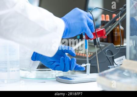 Technicien de laboratoire tenant une électrode en verre pour mesurer le pH de la solution à l'aide d'un pH-mètre. Laboratoire d'analyse ou d'électrochimie, laboratoire Banque D'Images