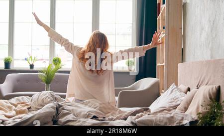 Une femme de race blanche se réveillant le matin dans un lit confortable sur des matelas orthopédiques souples étirements commence la nouvelle journée. Une fille s'éveille dans la chambre à coucher de l'hôtel Banque D'Images