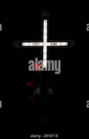 Un membre de l'Hermandad del Santo Cristo de los Artilleros porte une croix illuminée lors d'une procession Semana Santa à Valladolid, en Espagne Banque D'Images